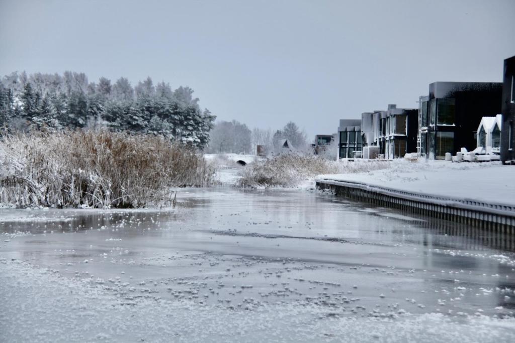 a river covered in snow next to some buildings at Aitvaru Terasos in Svenele