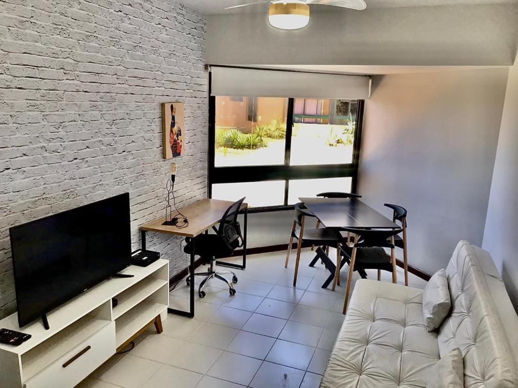 a living room with a couch and a tv and a table at Flat vista mar com estacionamento incluído in Salvador
