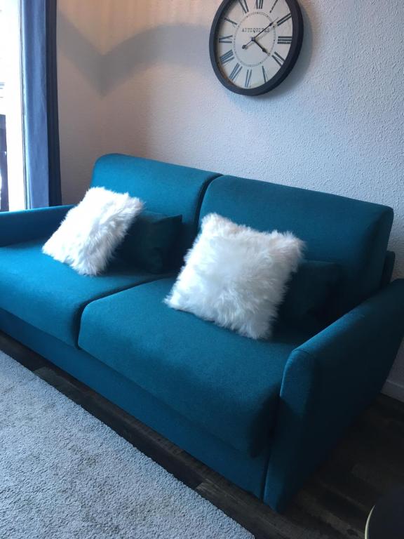 um sofá azul com duas almofadas e um relógio na parede em Studio 1 cabine chalet club III refait à neuf em Tignes