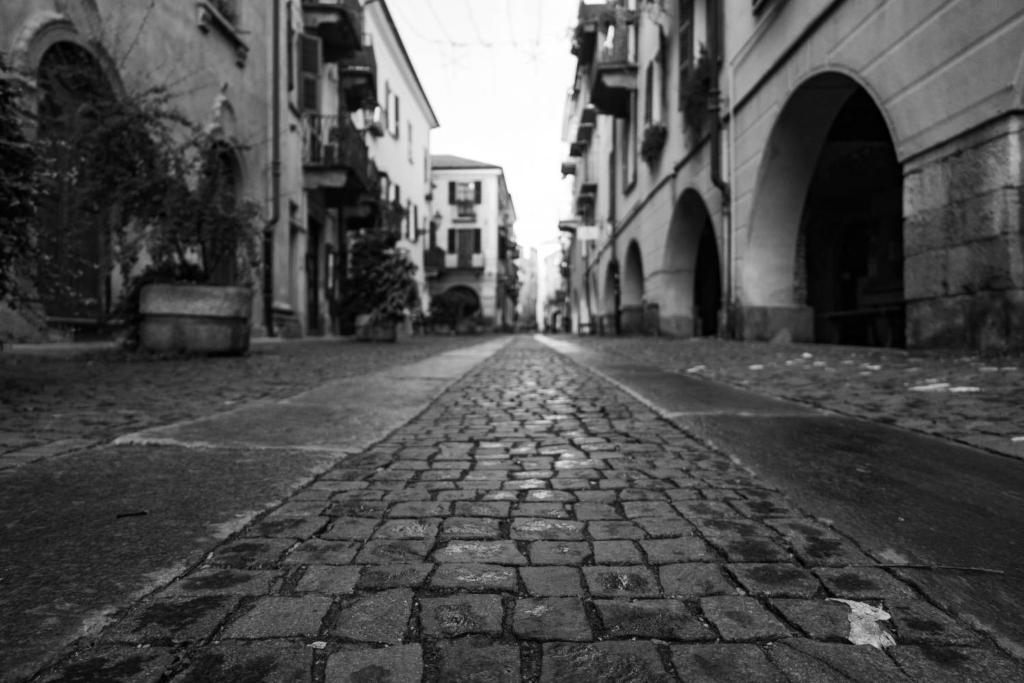 an empty cobblestone street in a city with buildings at La contrada in Cuneo