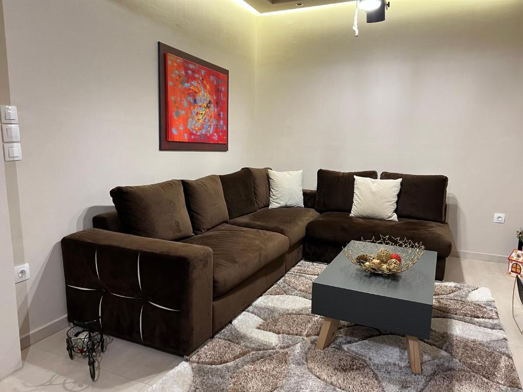 ein Wohnzimmer mit einem braunen Sofa und einem Tisch in der Unterkunft Petite Luxury Urban House in Tríkala