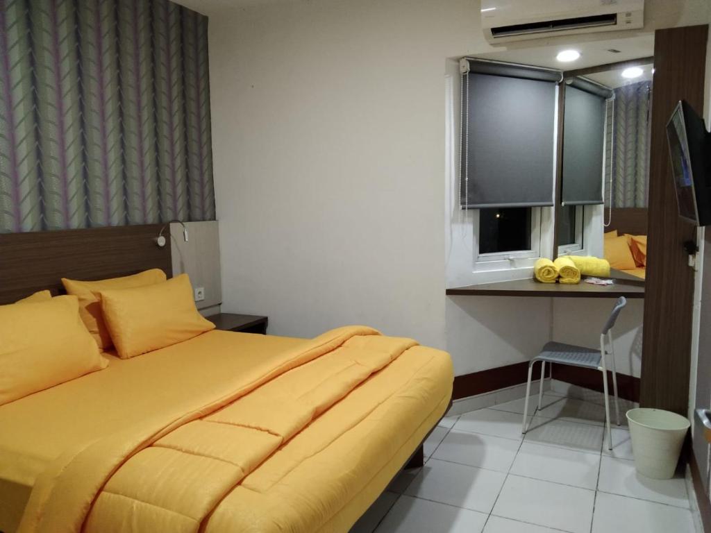 um quarto com uma cama amarela e uma secretária em SMART Dream Inn em Tangerang