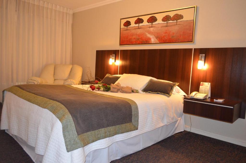 a hotel room with a large bed with flowers on it at Hotel Don Eduardo in Temuco