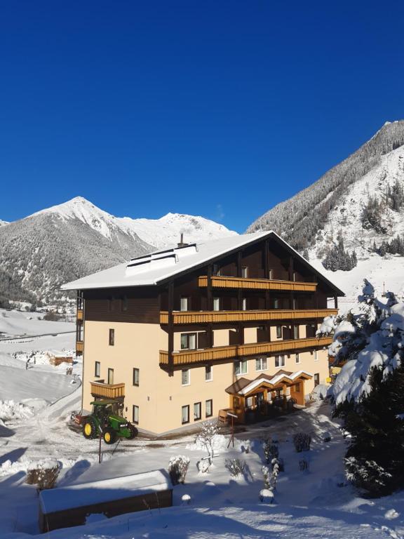 a large building in the snow with mountains in the background at Hotel Pension Oswald in Mallnitz