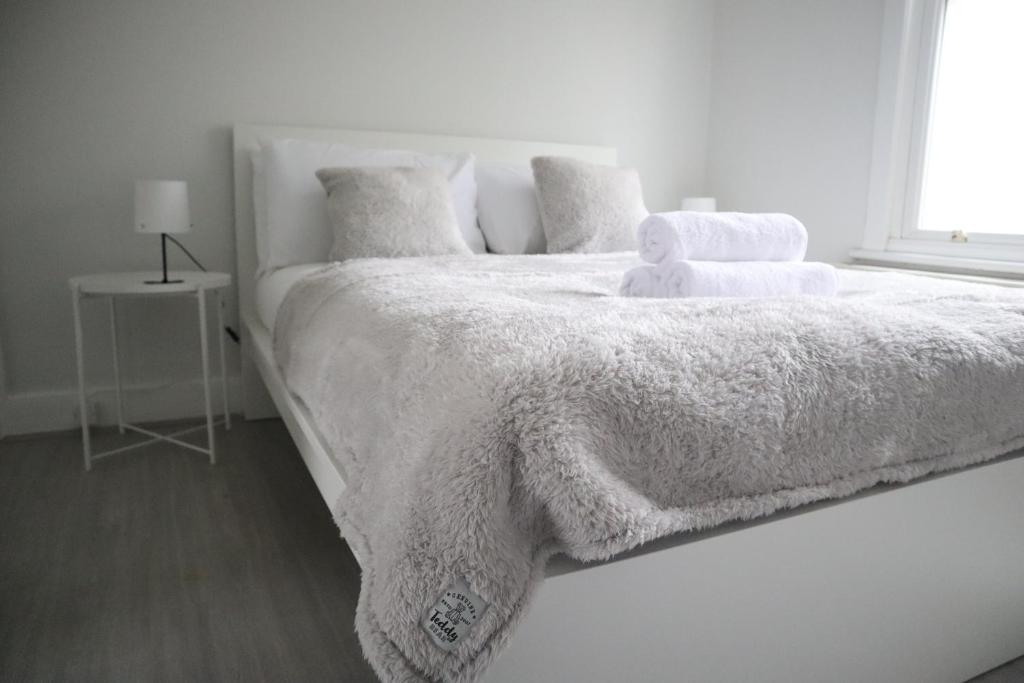 a white bedroom with a white bed with a teddy bear on it at Twelve Thirty Serviced Apartments - 2 Croydon in South Norwood