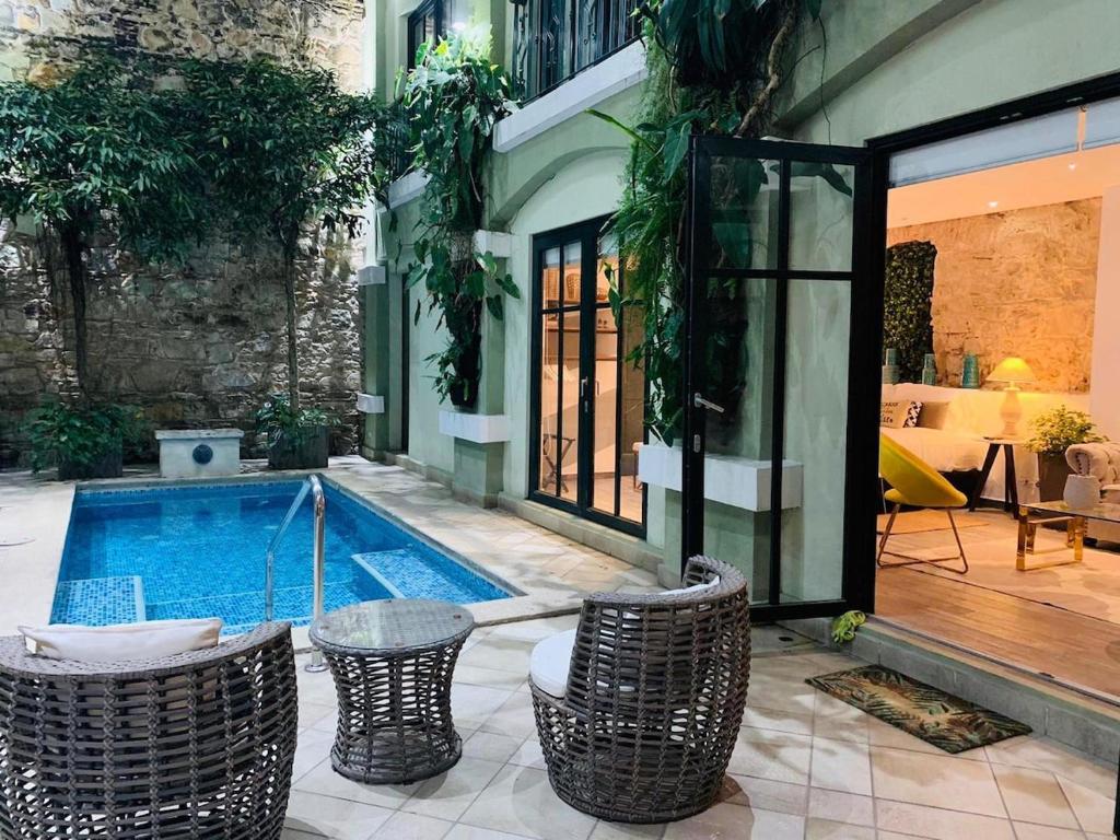 a swimming pool in a courtyard with wicker chairs at AmazINN Places Casco Viejo unique Desing and Pool VII in Panama City