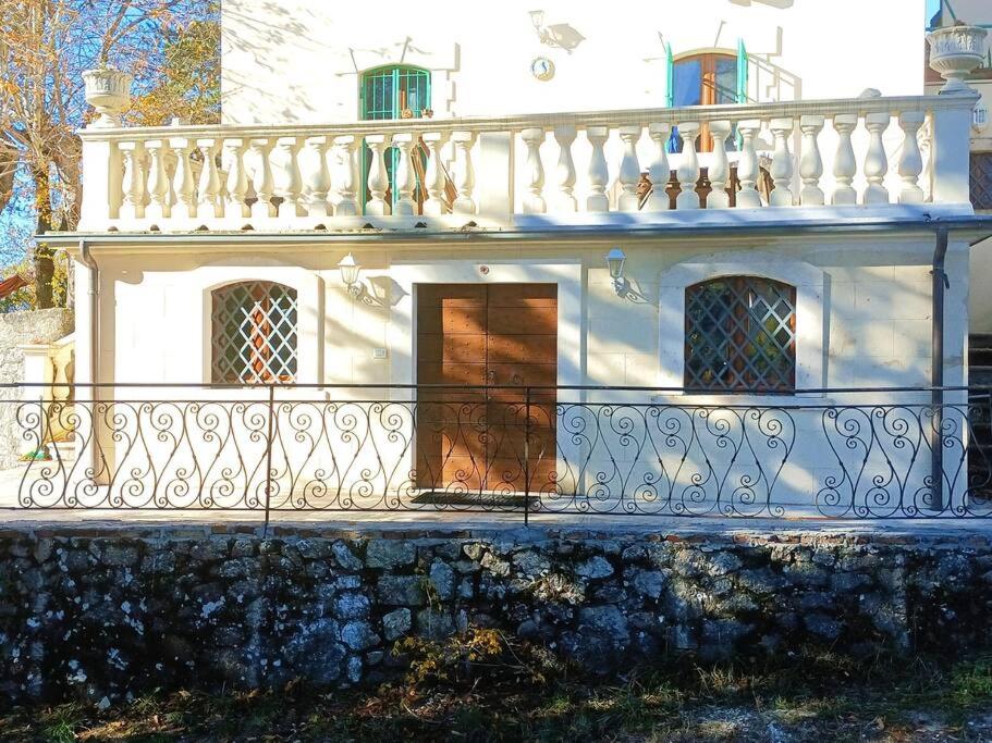een wit huis met een balkon en een hek bij La Fioraia bilocale con giardino in LʼAquila