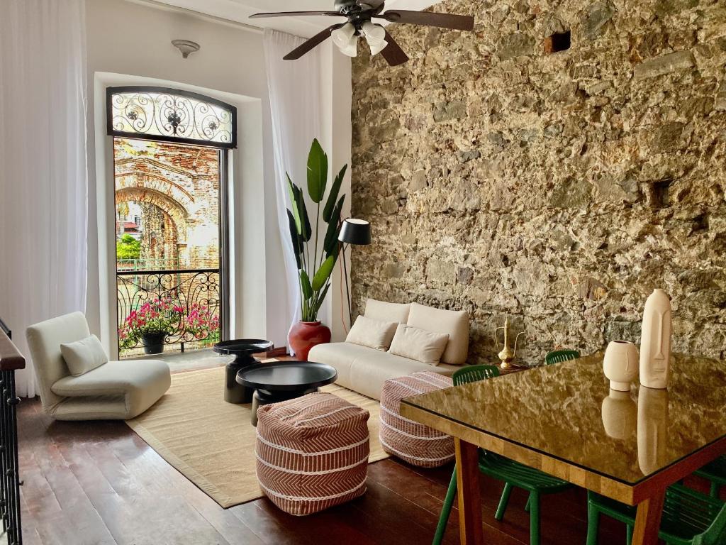 a living room with a couch and a stone wall at AmazINN Places Casco Viejo relaxing Views and Sound of the Sea in Panama City