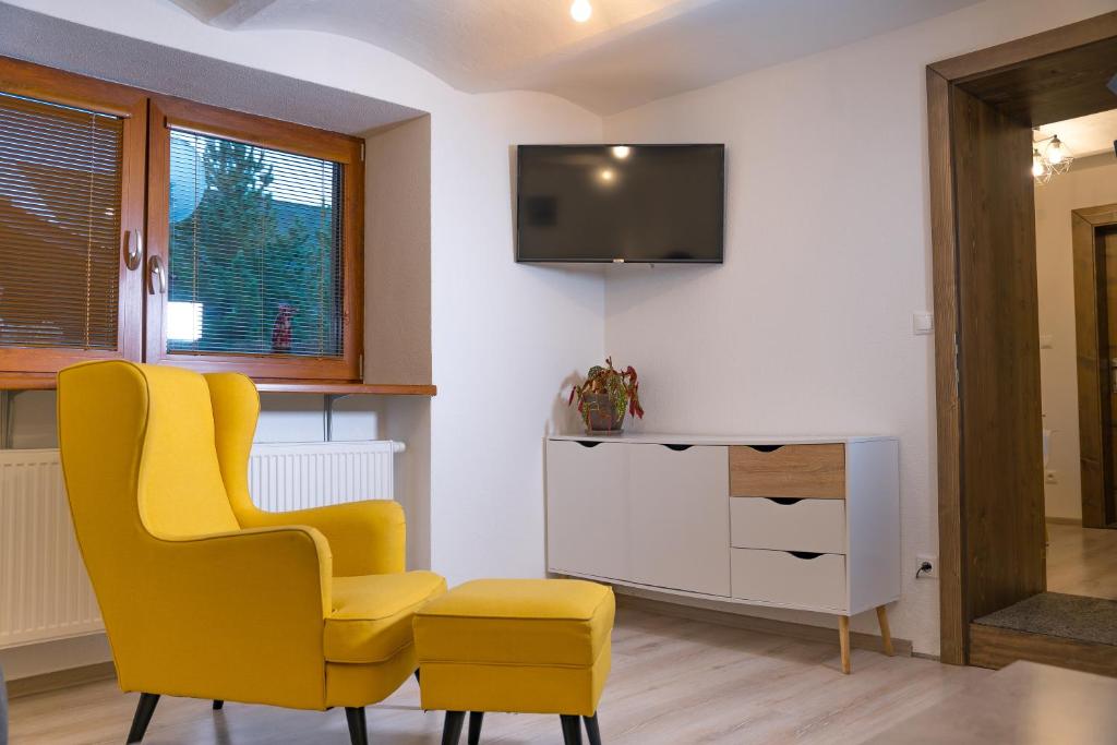 sala de estar con silla amarilla y TV en Tatry Low Guesthouse, en Stará Lesná