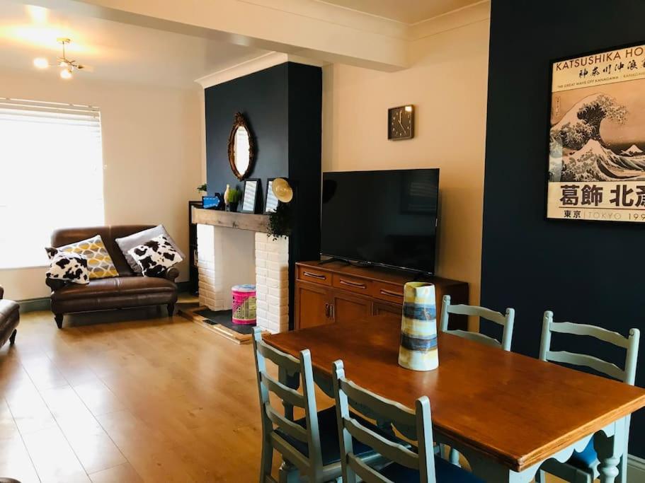 ein Wohnzimmer mit einem Tisch und einem TV in der Unterkunft Spacious 3 bed house near beach! in Lowestoft