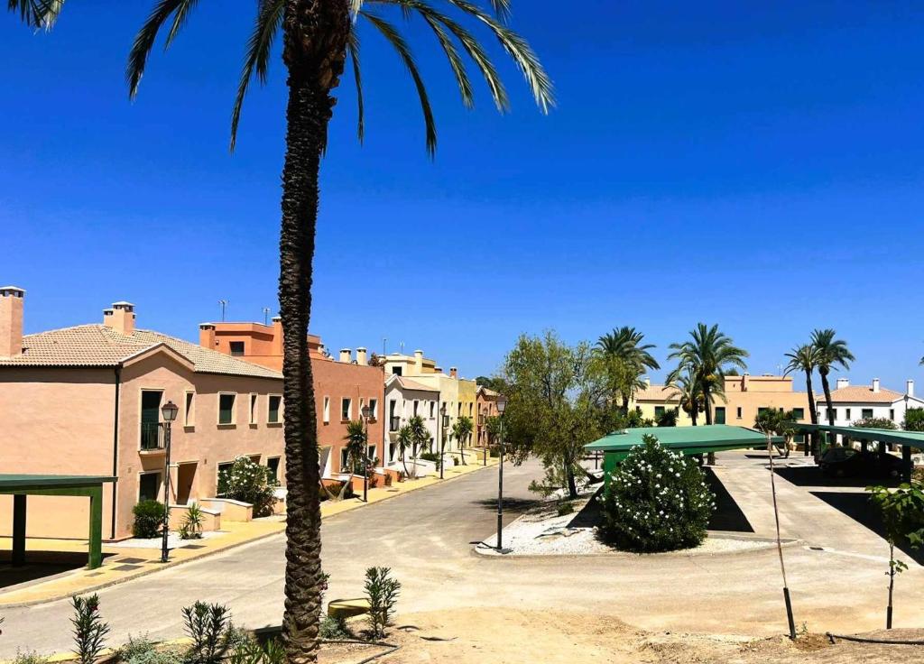 une rue de la ville avec des palmiers et des bâtiments dans l'établissement Villas Rurales Arroyovil, à Mancha Real