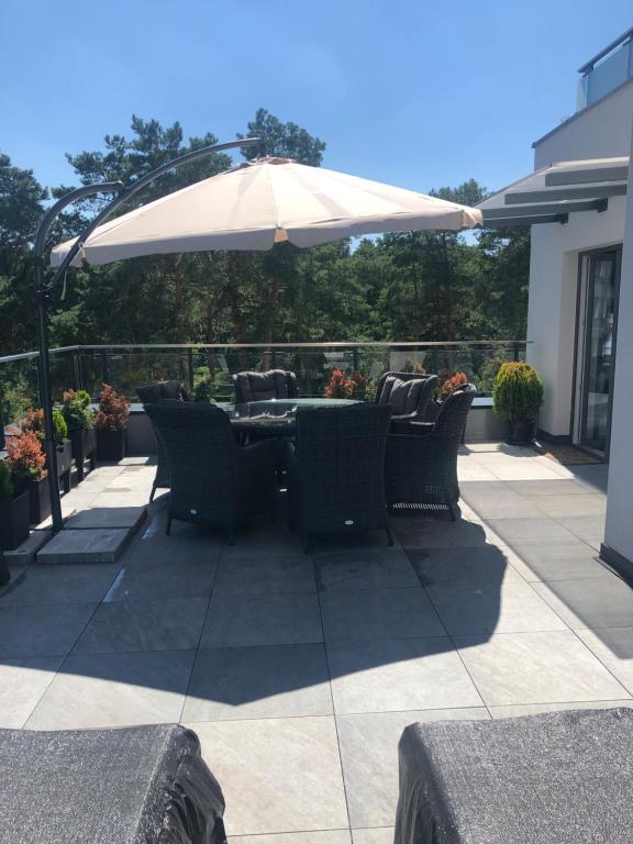 stół i krzesła pod parasolem na patio w obiekcie Apartament Business&Living No 73 z jacuzzi Nad Zalewem w Cedzynie i miejscem parkingowym w hali garażowej w mieście Cedzyna