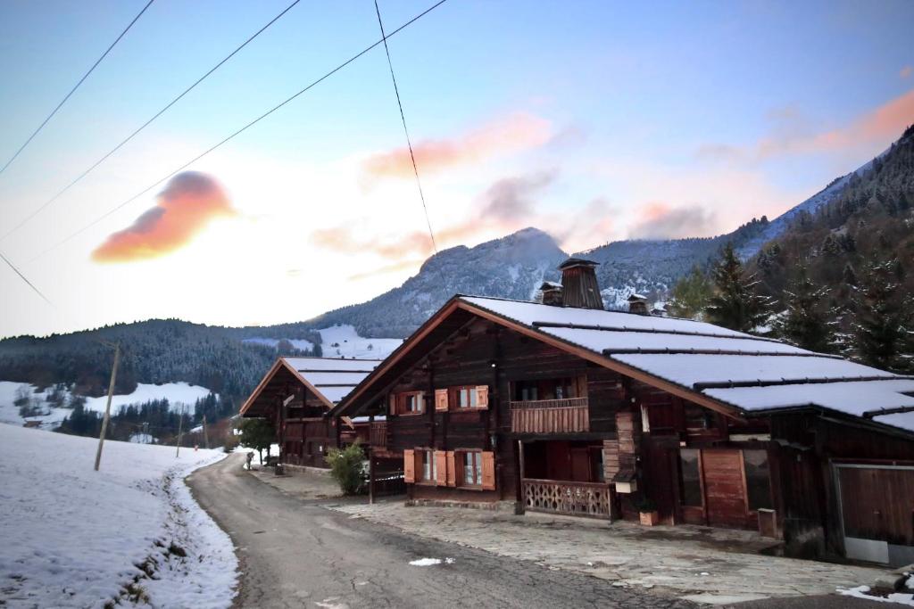 a log cabin in the mountains with snow on the roof at LACHAT appartement en chalet typique in Le Grand-Bornand