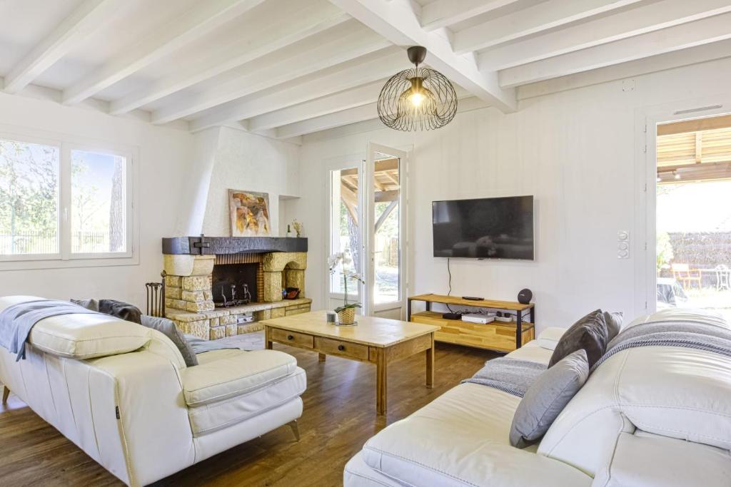 a living room with two white couches and a fireplace at Villa de la Côte - Welkeys in Labenne