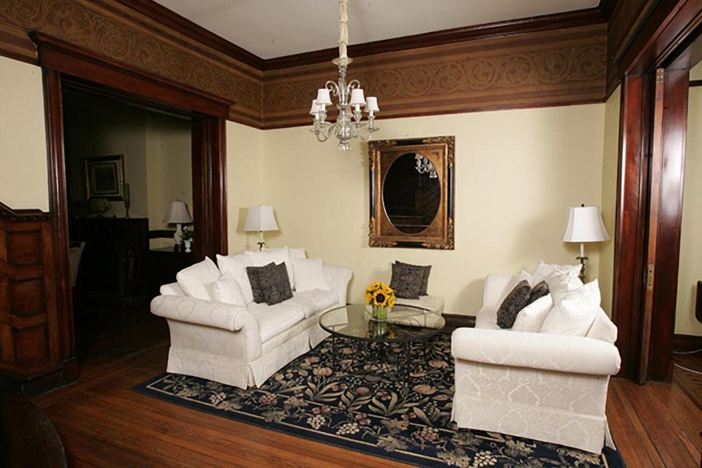 a living room with two white chairs and a table at Morgan State House Inn in Albany