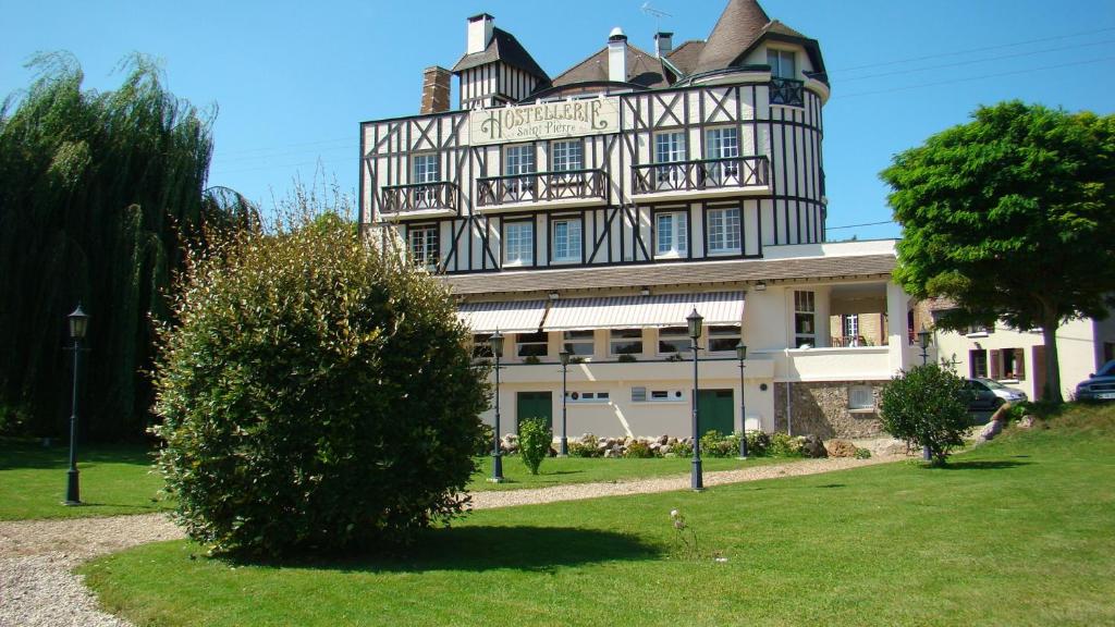 un gran edificio con un árbol delante en Hostellerie Saint Pierre en Saint-Pierre-du-Vauvray