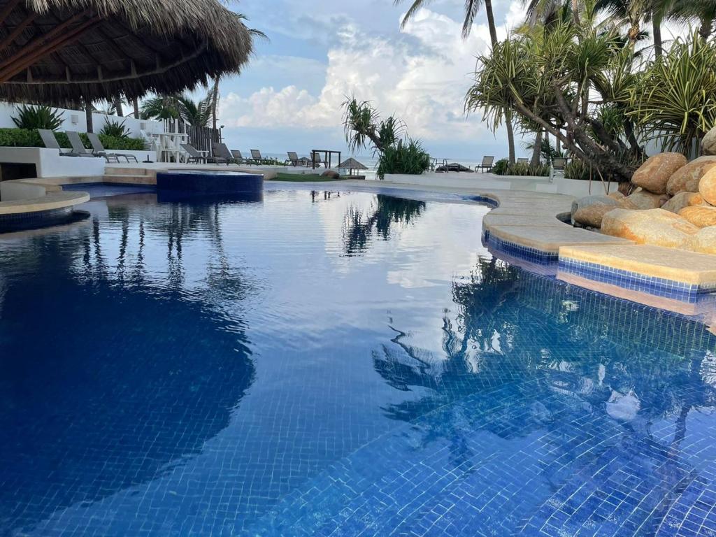 - une piscine d'eau bleue avec des palmiers dans l'établissement Exclusivo Departamento con acceso a playa, à Acapulco