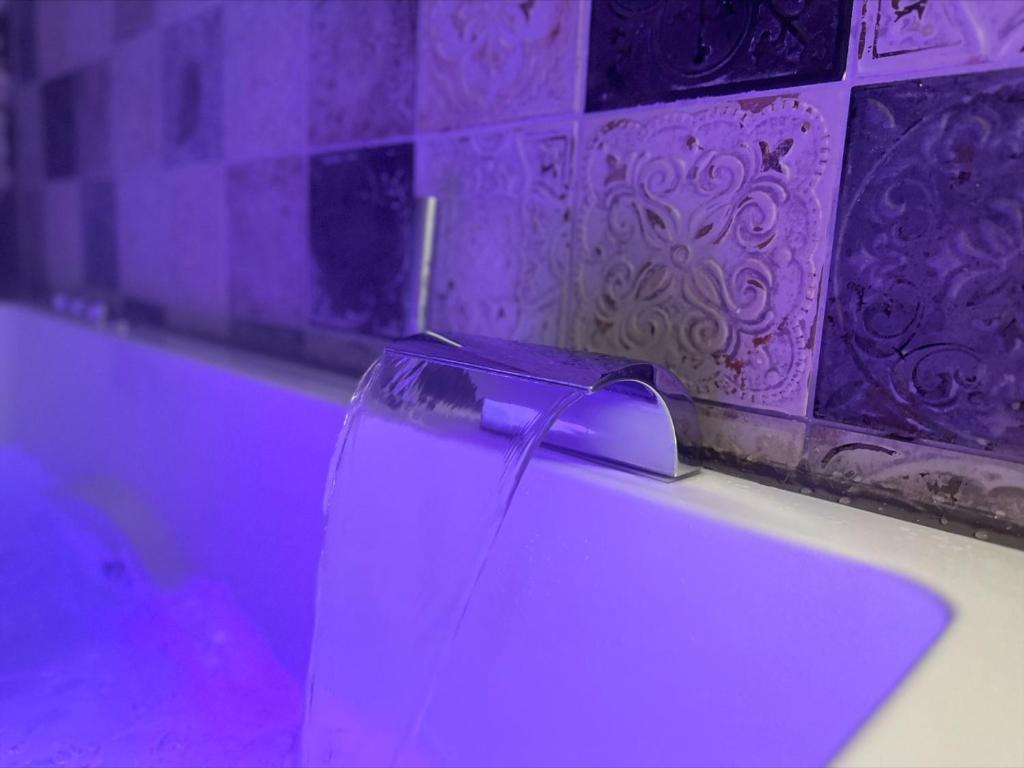 een badkamer met een wit bad met paarse verlichting bij Les pieds dans l'eau SWEET HOME in Corné