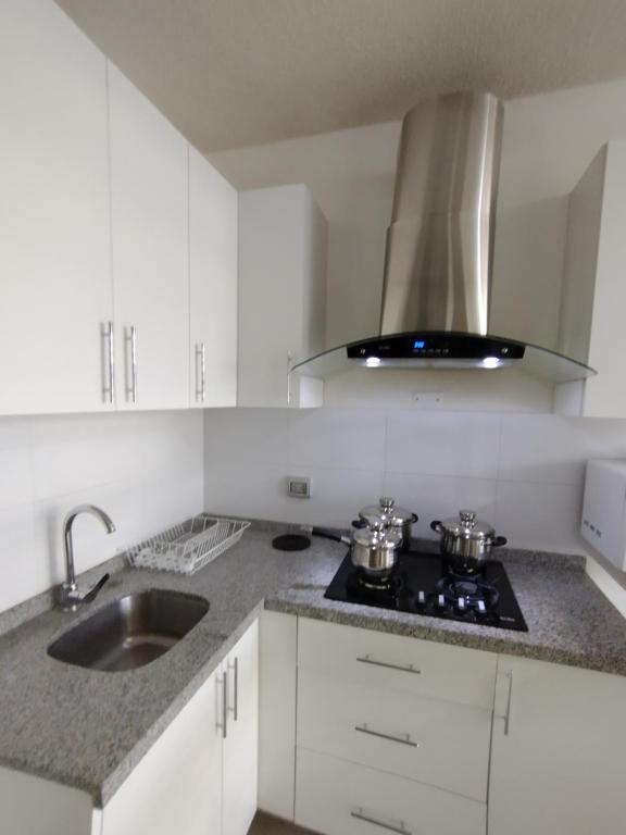 a white kitchen with a stove and a sink at Suites Apart Piura in Piura