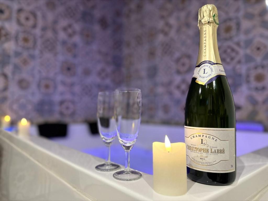 una bottiglia di champagne e due bicchieri su un tavolo di Les pieds dans l'eau ALOHA a Corné