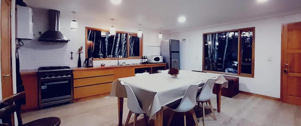 eine Küche mit einem Tisch und Stühlen im Zimmer in der Unterkunft Zorro Azul - Corazón de la Isla - Tierra del Fuego in Tolhuin