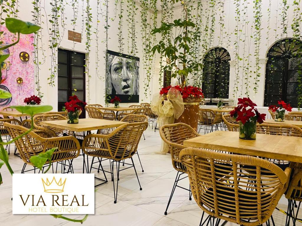 Vía Real Hotel Boutique في Atotonilco el Alto: مطعم بطاولات وكراسي مع صورة لسيدة