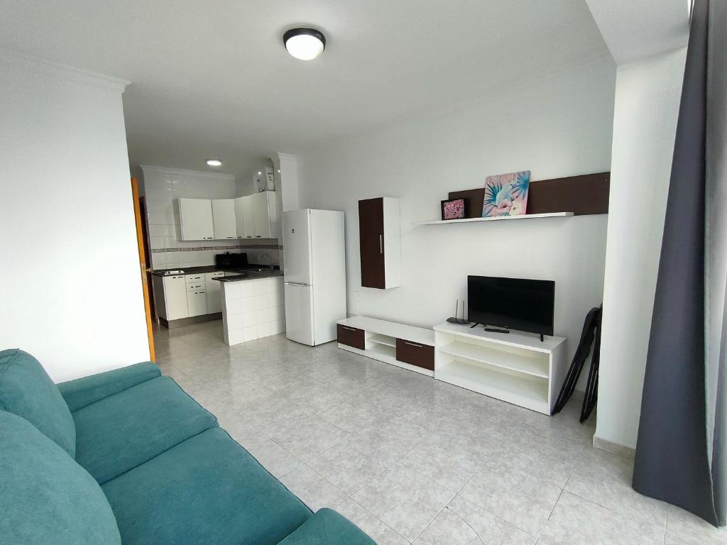 sala de estar con sofá y TV en Apartamentos Las Canteras Arena, en Las Palmas de Gran Canaria