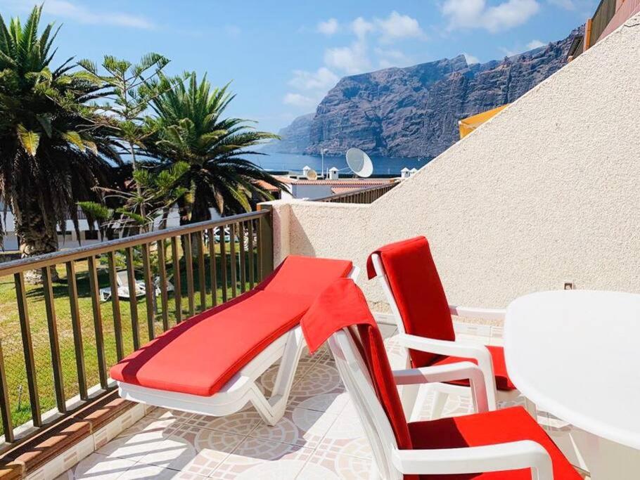 - deux chaises rouges et blanches et une table sur un balcon dans l'établissement Calle Tamara 2-9, à Santiago del Teide