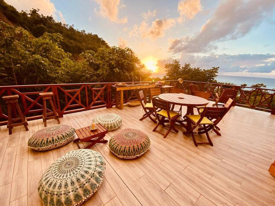 drewniany taras ze stołem i krzesłami oraz zachodem słońca w obiekcie The Palms - Caribbean Paradise w mieście Playa Aguadulce