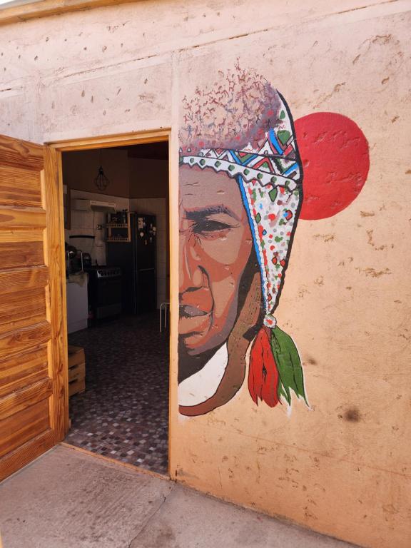 a painting of a woman with a hat on a wall at Las Casas Hostel Atacama in San Pedro de Atacama
