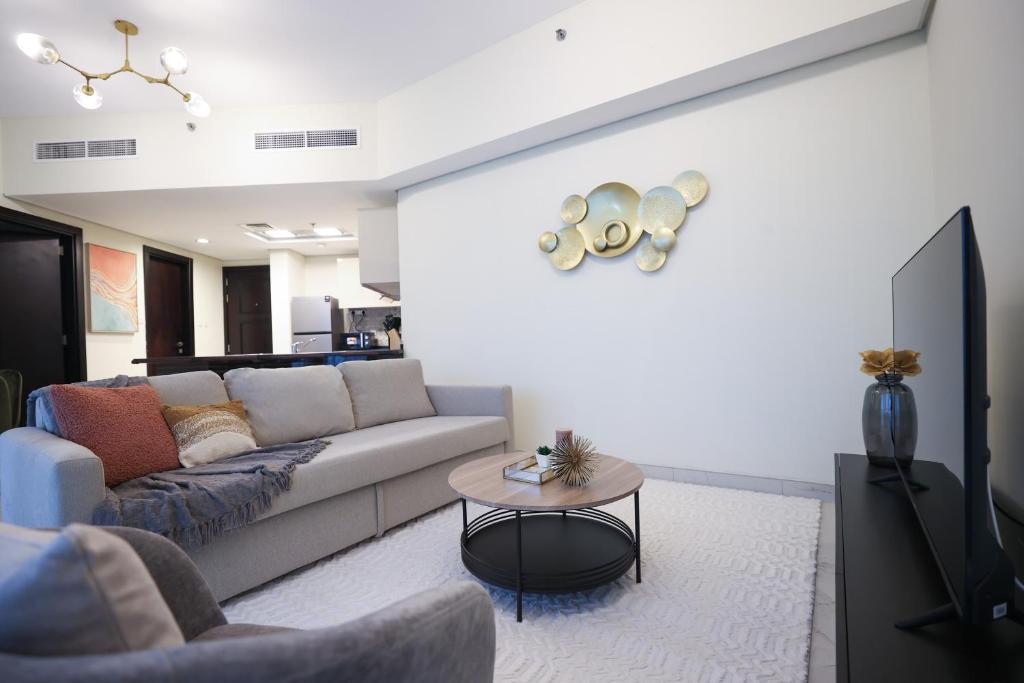 ein Wohnzimmer mit einem Sofa und einem Tisch in der Unterkunft Elite LUX Holiday Homes - Modern One Bedroom Apartment in MAG 5, Dubai South in Dubai