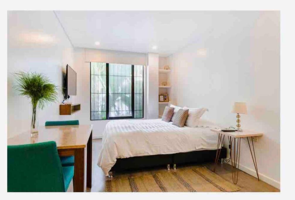 a bedroom with a bed and a desk and a window at Confortable apartamento con la perfecta ubicación! in Bogotá