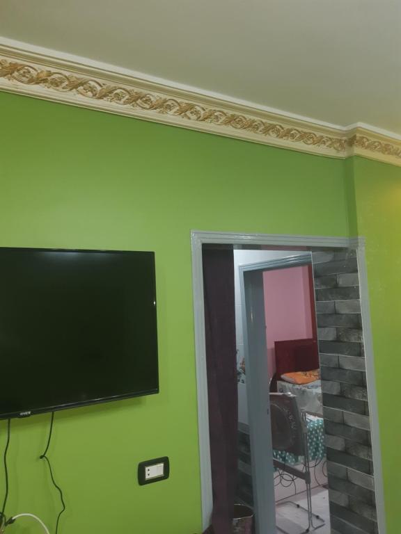 Elle comprend une télévision à écran plat suspendue sur un mur vert. dans l'établissement شقة فندقية فاخرة بدمياط قريبة من الميناء, à Dumyāţ al Jadīdah
