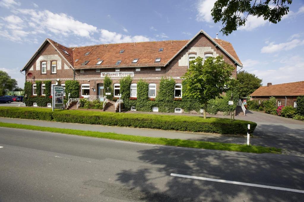 uma grande casa de tijolos ao lado de uma rua em Frieslandstern - Ferienhof und Hotel em Wangerland