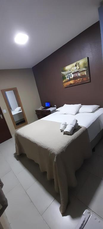 sypialnia z dużym łóżkiem z białą pościelą i poduszkami w obiekcie Pousada Tartaruga w mieście Cumbuco