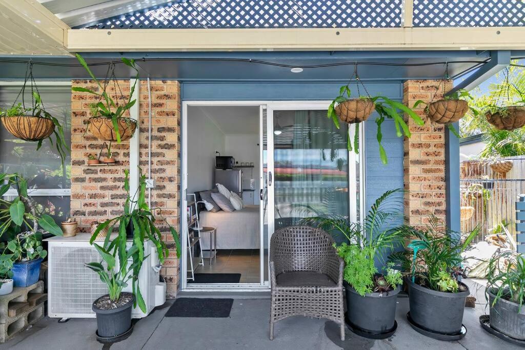 a patio with potted plants and a chair at The Brick Batch - holiday unit! in Bellara