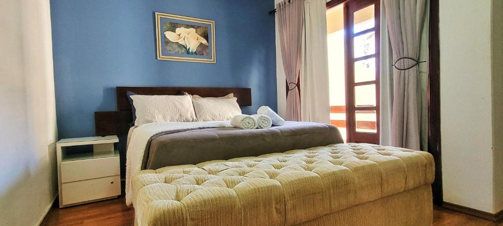 a bedroom with a bed with a ottoman next to a window at Casa Próximo ao Centro Agradável e Inteligente in Poços de Caldas