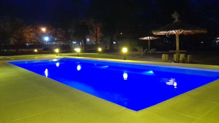 una gran piscina azul por la noche en Cabañas La Deseada (Ranchos, Buenos Aires) en Ranchos