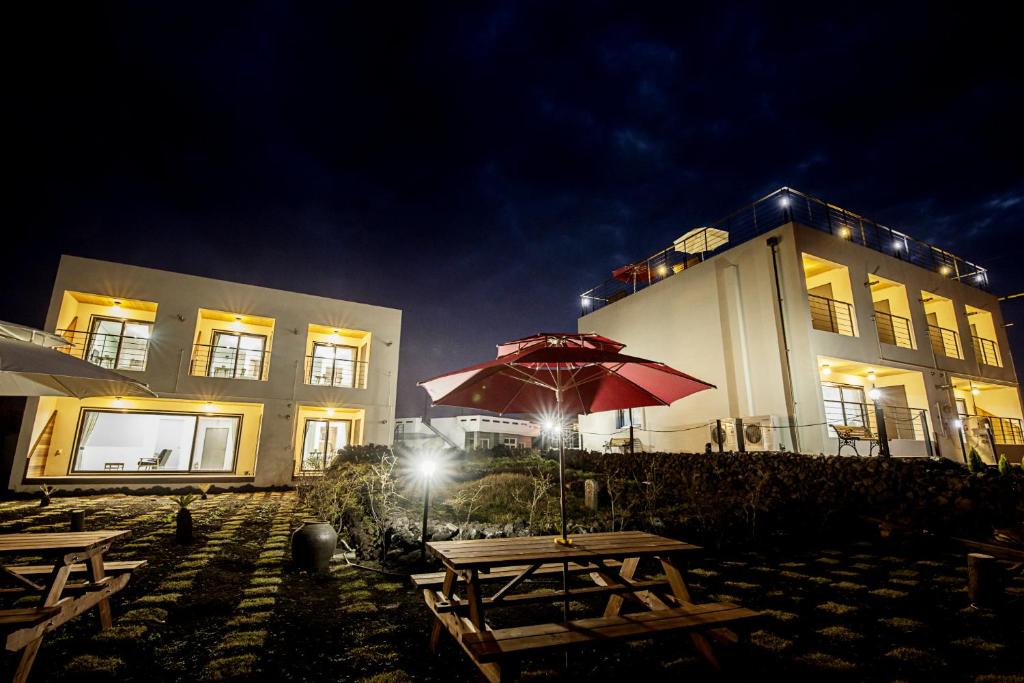 a picnic table with an umbrella in front of a building at Handongijen Pension in Jeju