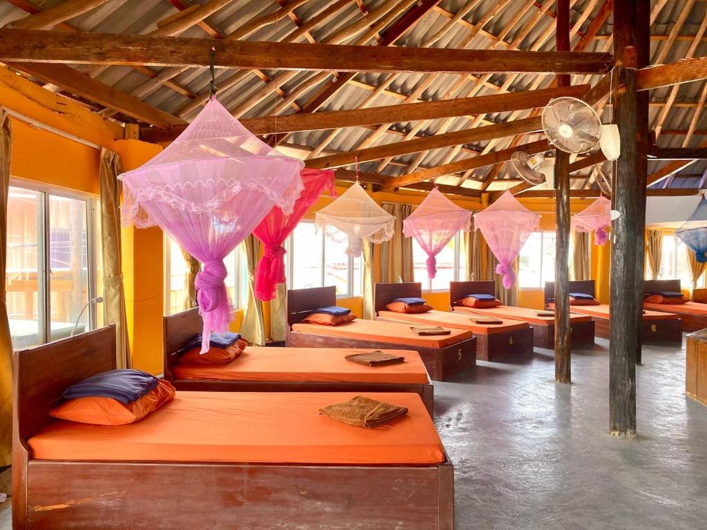 a room with rows of beds with umbrellas at M'pay Bay Guesthouse in Koh Rong Sanloem