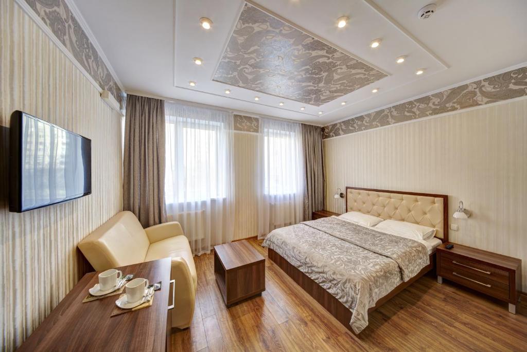 1 dormitorio con cama, mesa y TV en Three Crowns Hotel en Leópolis