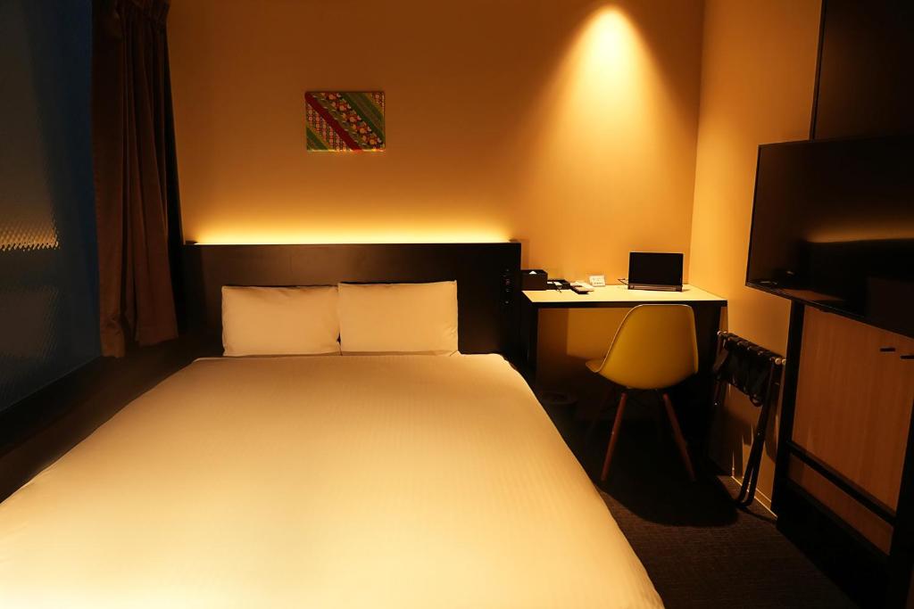 Schlafzimmer mit einem Bett und einem Schreibtisch mit einem Laptop in der Unterkunft Nplus HOTEL Higashikanda-akihabara in Tokio