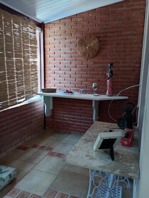 a room with a brick wall and a white table at Casa da Roseli - Pitangueiras in Guarujá