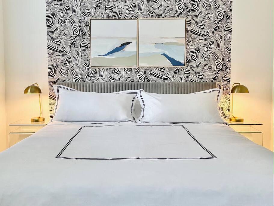 a bedroom with a white bed with two lamps at The Clemente Mt. Washington by Luxe PGH in Pittsburgh