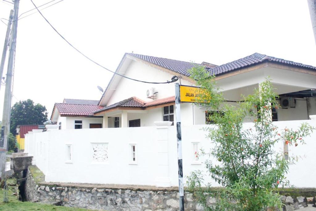 a white fence in front of a house at Homestay Mokde in Muar