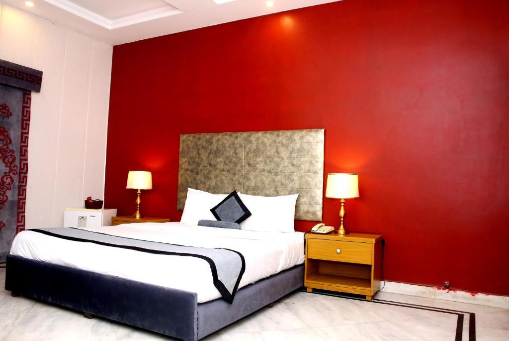 a bedroom with a large bed with a red wall at Premier inn Mall Lahore in Lahore
