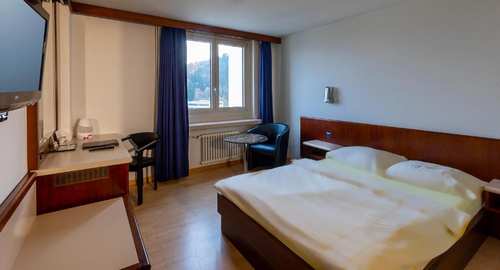 a hotel room with a bed and a desk and a window at Hotel Linde - 24h Self Check-in in Baden