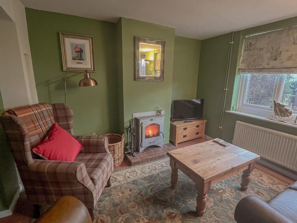 a living room with a couch and a table and a fireplace at Lavender Cottage - Knodishall - Newly renovated 2 bed holiday home, near Aldeburgh, Leiston and Thorpeness in Aldringham