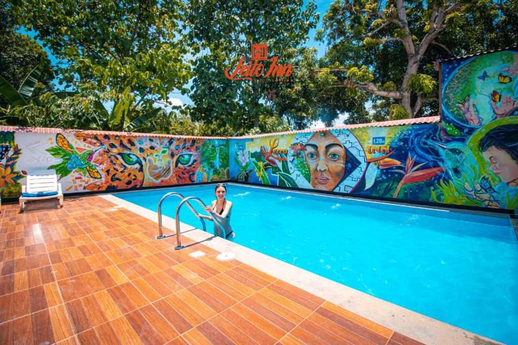 una donna seduta in piscina con un murale di Hotel Leito Inn a Tarapoto