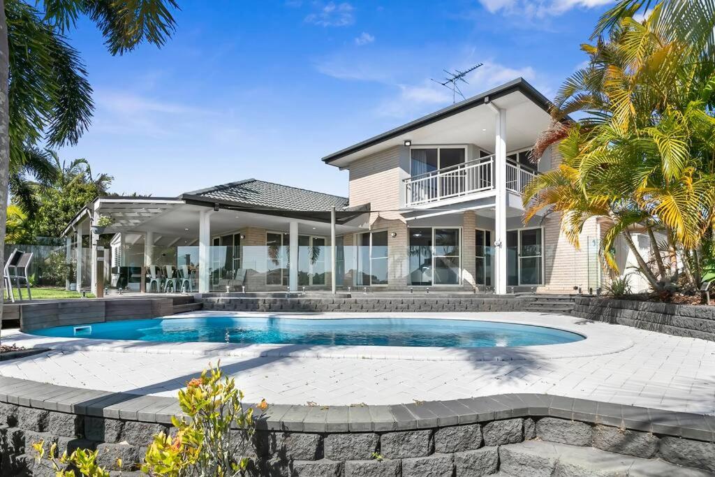 a house with a swimming pool in front of it at Voyagers Resort - Stunning home! in Banksia Beach